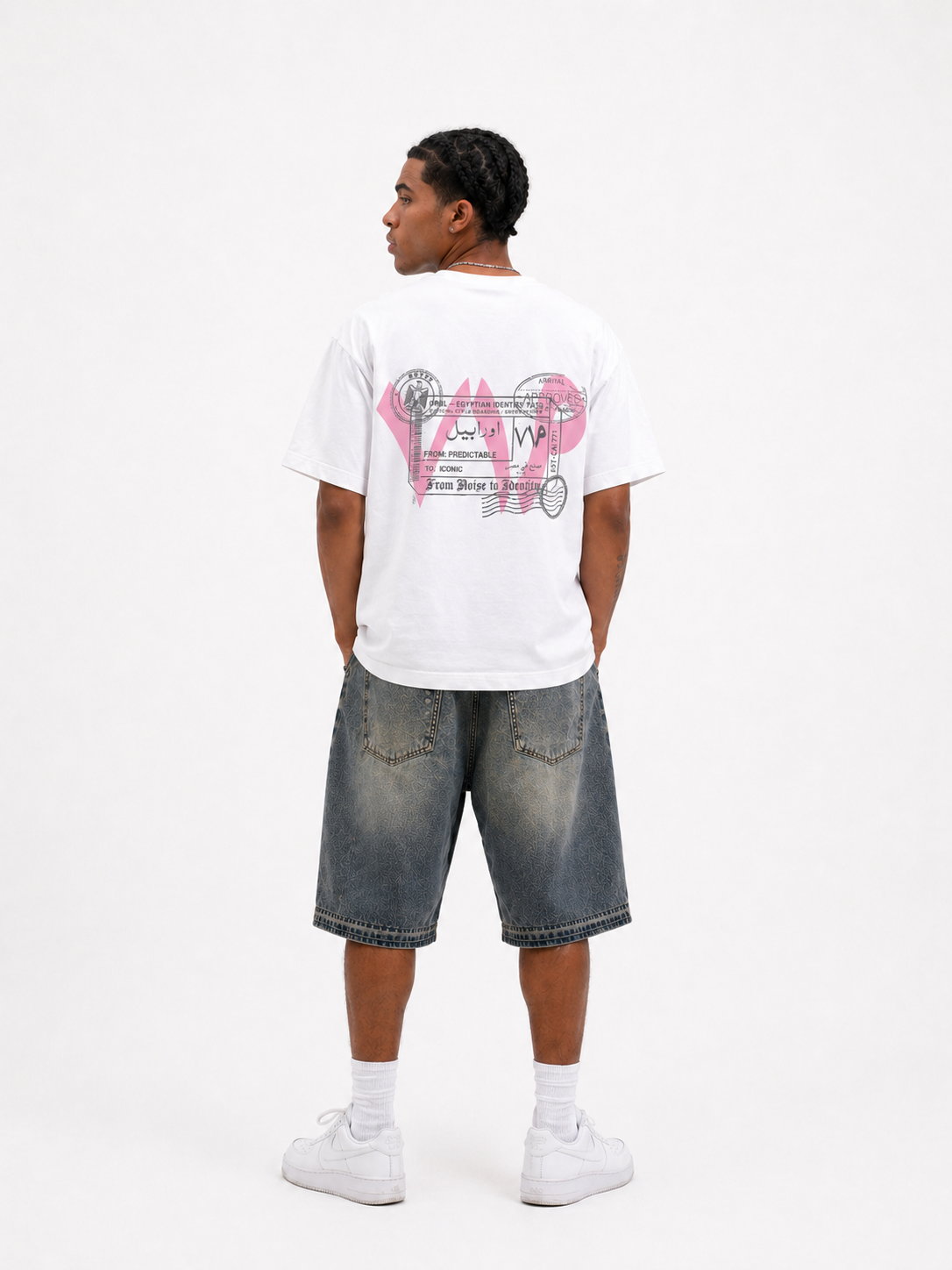 Person wearing a white t-shirt with pink graphics and text, paired with denim shorts on a white background